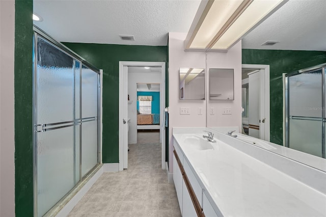 bathroom featuring vanity, a shower with shower door, and a textured ceiling