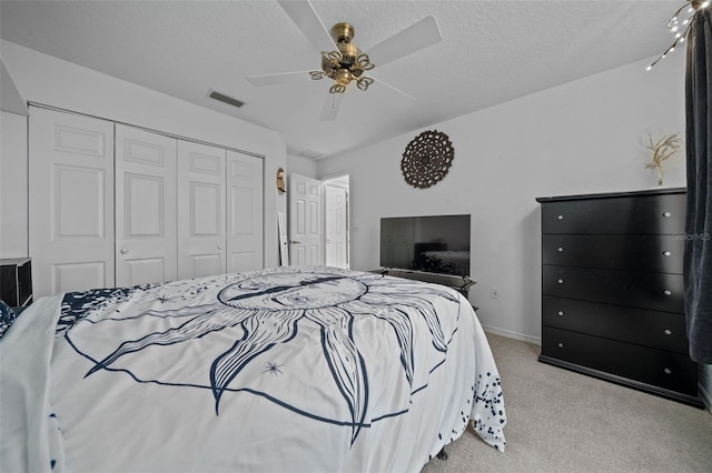 bedroom featuring light colored carpet, a textured ceiling, ceiling fan, and a closet