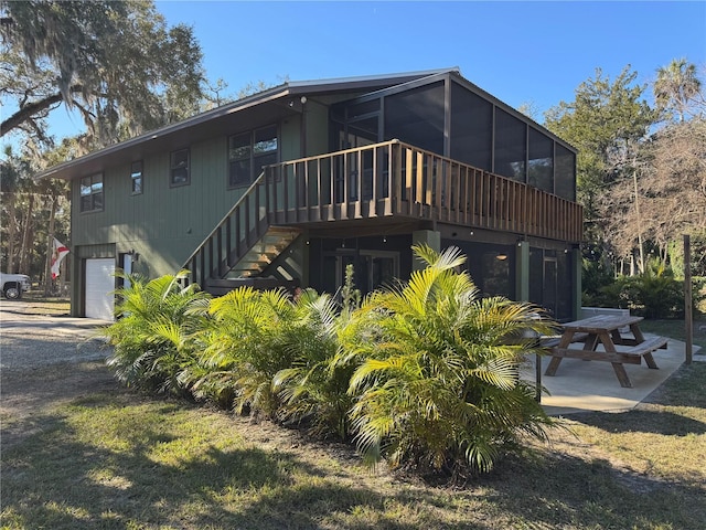 back of property with a garage, a patio, and a sunroom