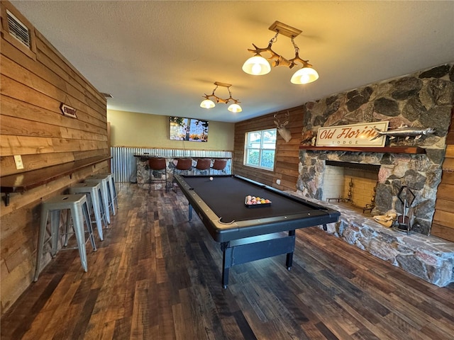 game room with a fireplace, indoor bar, pool table, dark wood-type flooring, and a textured ceiling