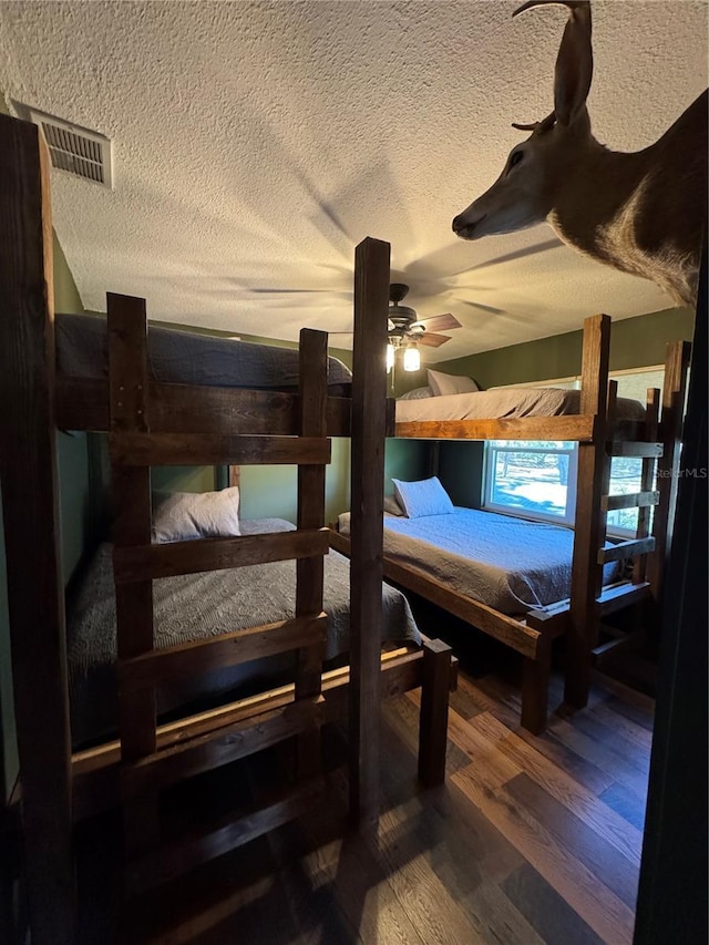 bedroom with ceiling fan, wood-type flooring, and a textured ceiling