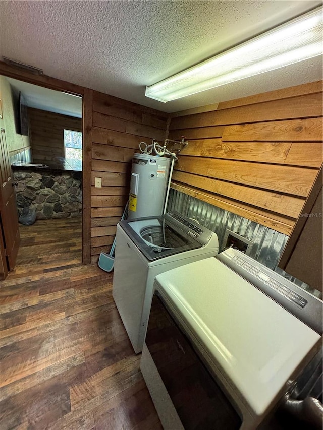 laundry area with wood walls, separate washer and dryer, dark wood-type flooring, electric water heater, and a textured ceiling