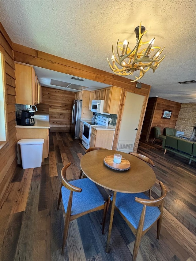 dining room featuring sink, wooden walls, and dark hardwood / wood-style floors