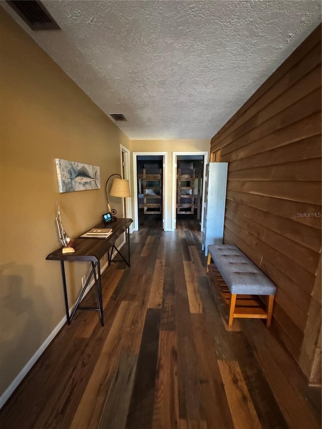 corridor featuring dark hardwood / wood-style flooring, a textured ceiling, and wood walls