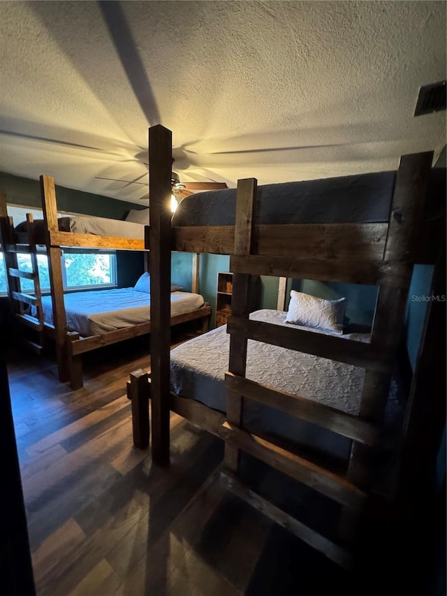 bedroom with ceiling fan, wood-type flooring, and a textured ceiling