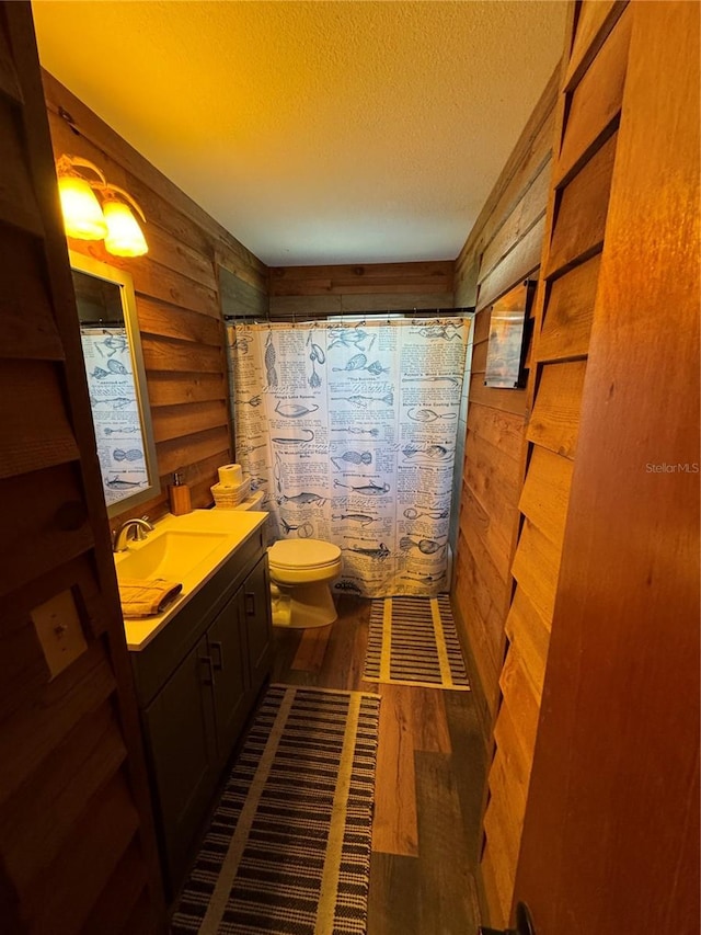 bathroom with hardwood / wood-style flooring, vanity, a textured ceiling, toilet, and walk in shower