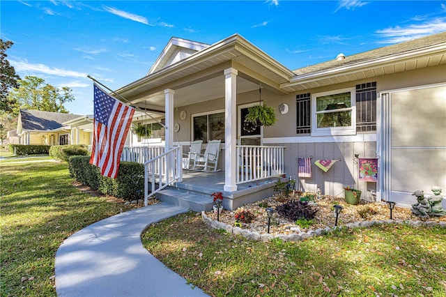 view of exterior entry featuring a porch and a yard