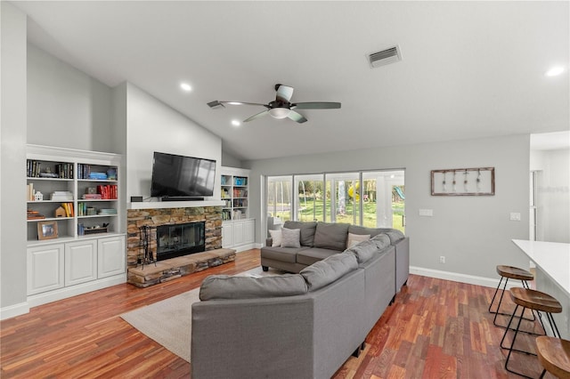 living room with a stone fireplace, vaulted ceiling, dark hardwood / wood-style floors, and ceiling fan