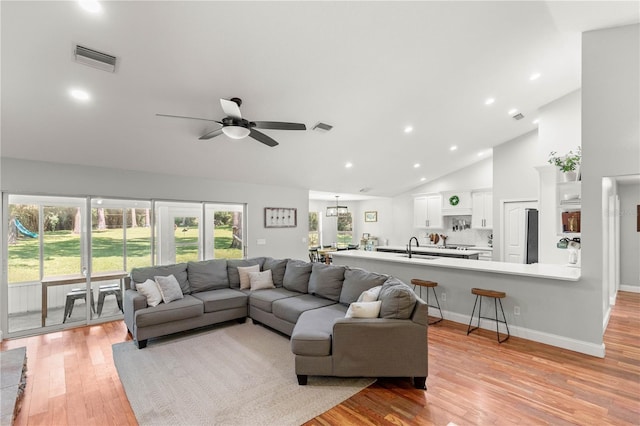 living room featuring ceiling fan, high vaulted ceiling, sink, and light hardwood / wood-style flooring
