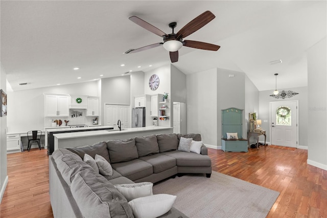 living room with sink, light hardwood / wood-style flooring, high vaulted ceiling, and ceiling fan