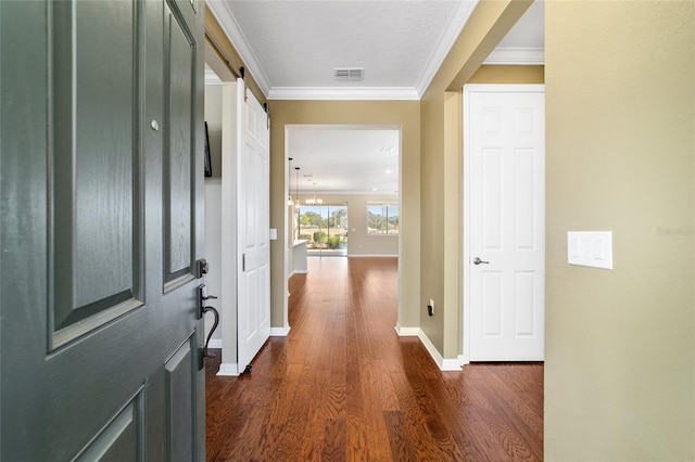 corridor with dark wood-type flooring, a barn door, and crown molding