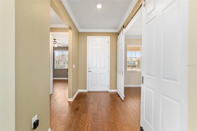 foyer featuring hardwood / wood-style flooring, crown molding, a barn door, and a wealth of natural light