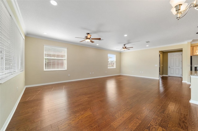 empty room with ornamental molding, dark hardwood / wood-style floors, and ceiling fan with notable chandelier