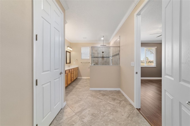 bathroom featuring vanity, crown molding, a healthy amount of sunlight, and a tile shower