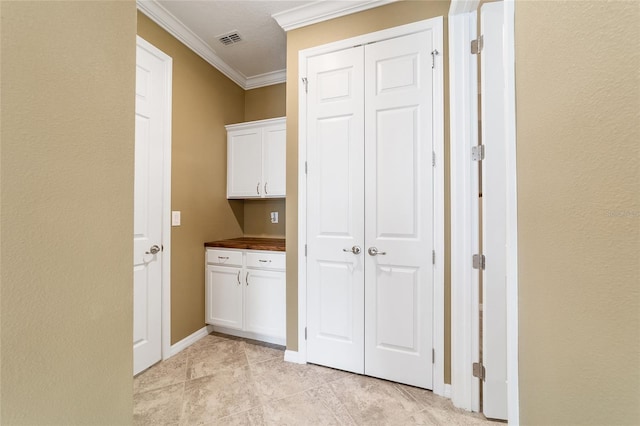 laundry area with light tile patterned floors and crown molding