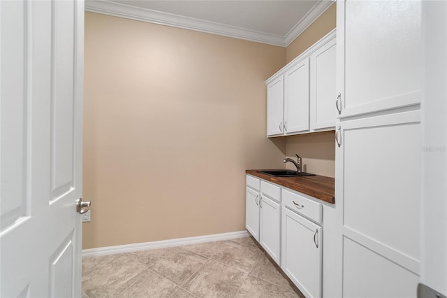 clothes washing area featuring light tile patterned flooring, ornamental molding, and sink