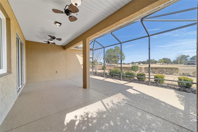 view of patio featuring a rural view, ceiling fan, and glass enclosure