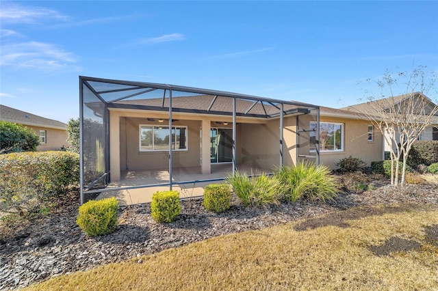 back of house featuring ceiling fan, glass enclosure, and a patio