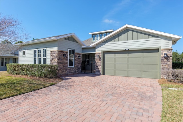 view of front facade featuring a garage, stone siding, decorative driveway, and board and batten siding