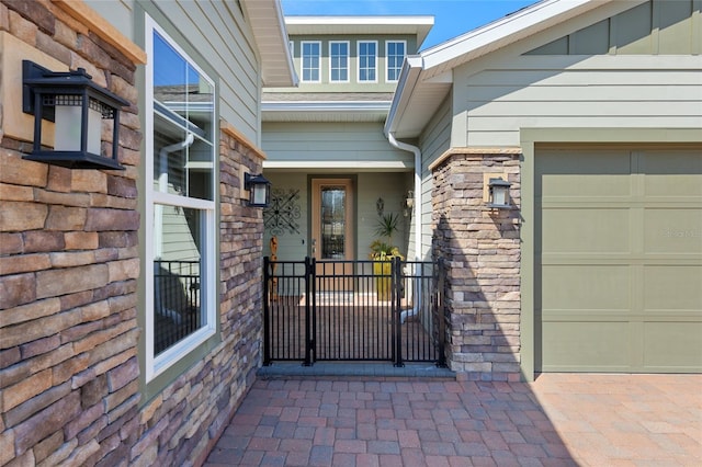 entrance to property featuring a garage and stone siding