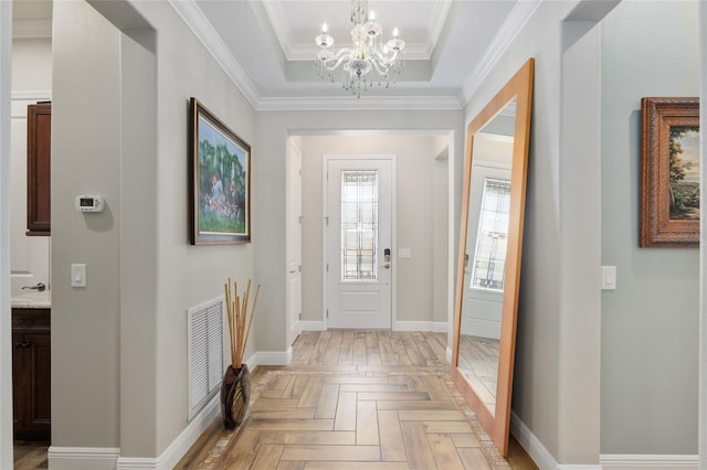 foyer featuring visible vents, baseboards, ornamental molding, a tray ceiling, and an inviting chandelier