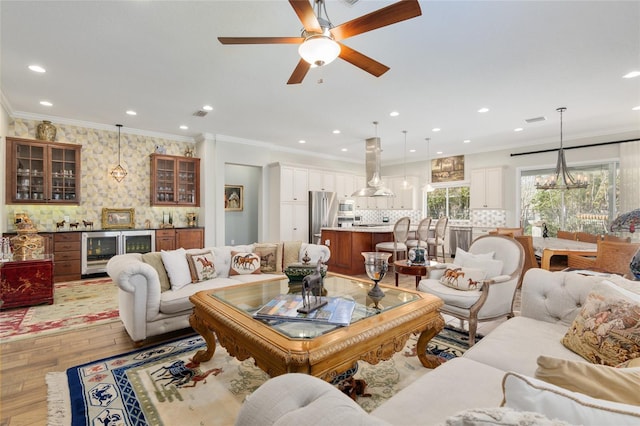 living area with wine cooler, recessed lighting, bar area, ornamental molding, and light wood finished floors