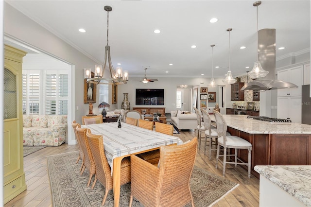 dining area with light wood-type flooring, crown molding, and recessed lighting