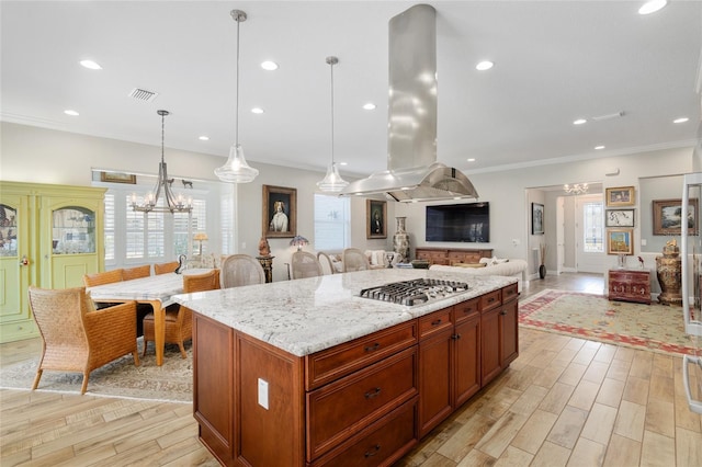 kitchen featuring visible vents, ornamental molding, open floor plan, island exhaust hood, and a chandelier