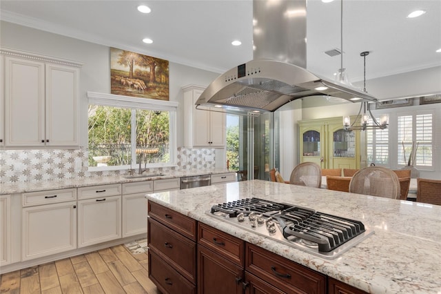 kitchen featuring pendant lighting, crown molding, stainless steel appliances, backsplash, and a sink