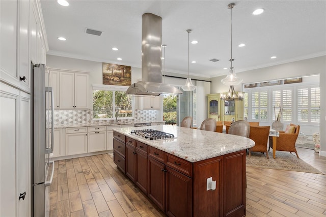 kitchen featuring ornamental molding, stainless steel appliances, tasteful backsplash, and island exhaust hood