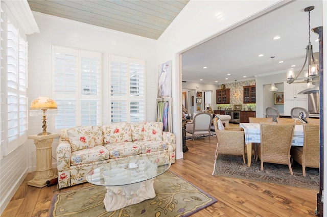 living room featuring light wood finished floors, a chandelier, crown molding, and recessed lighting