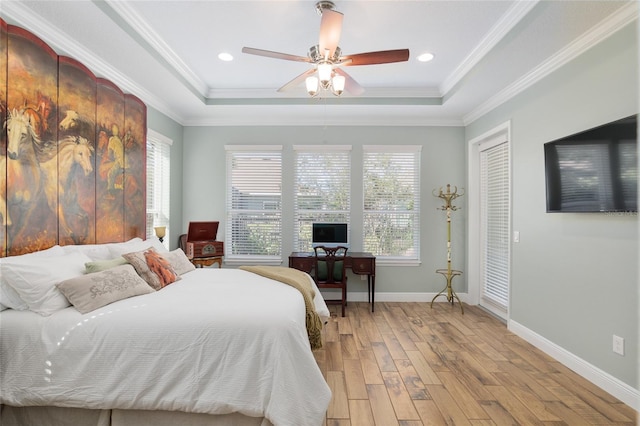 bedroom featuring light wood-style flooring, multiple windows, a tray ceiling, and baseboards