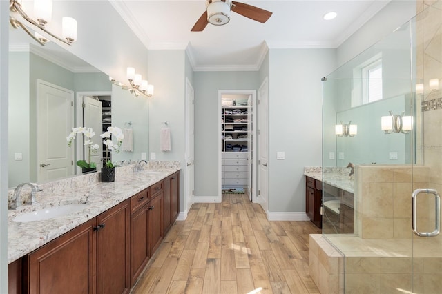 full bathroom featuring ornamental molding, wood finished floors, a stall shower, and a sink