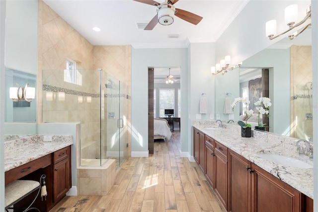 bathroom with a stall shower, ornamental molding, a sink, and wood finished floors