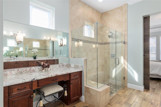 full bath featuring a stall shower, connected bathroom, vanity, wood finished floors, and baseboards