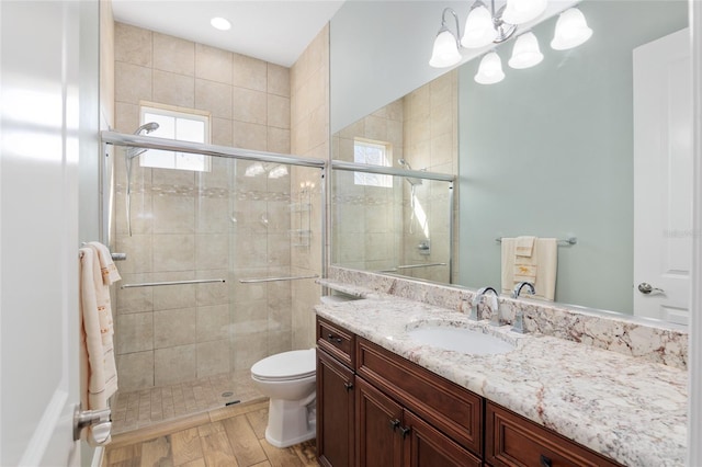 bathroom featuring toilet, a tile shower, wood finished floors, and vanity