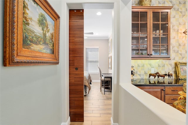 corridor featuring baseboards, recessed lighting, wood finished floors, and crown molding