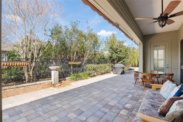 view of patio featuring outdoor dining space, grilling area, fence, and a ceiling fan