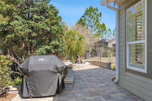 view of patio / terrace featuring a grill, a fire pit, and fence