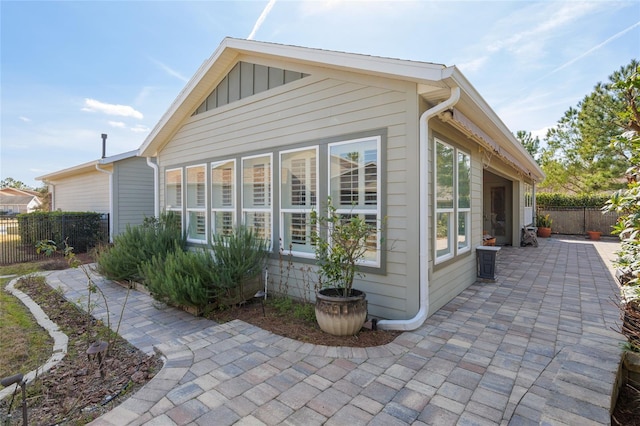 view of home's exterior with board and batten siding, a patio, and fence