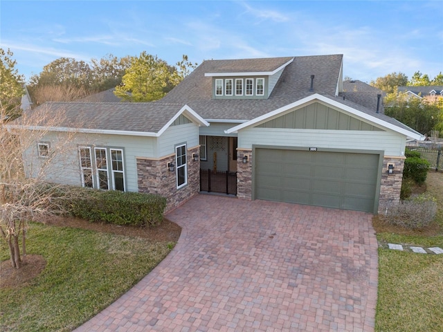 view of front facade featuring an attached garage, stone siding, roof with shingles, decorative driveway, and board and batten siding