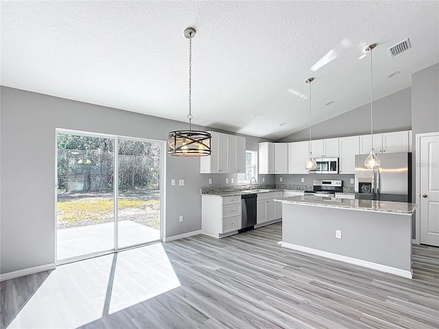 kitchen featuring sink, a kitchen island, pendant lighting, stainless steel appliances, and white cabinets