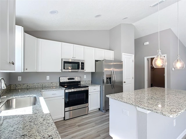 kitchen with sink, vaulted ceiling, hanging light fixtures, stainless steel appliances, and white cabinets