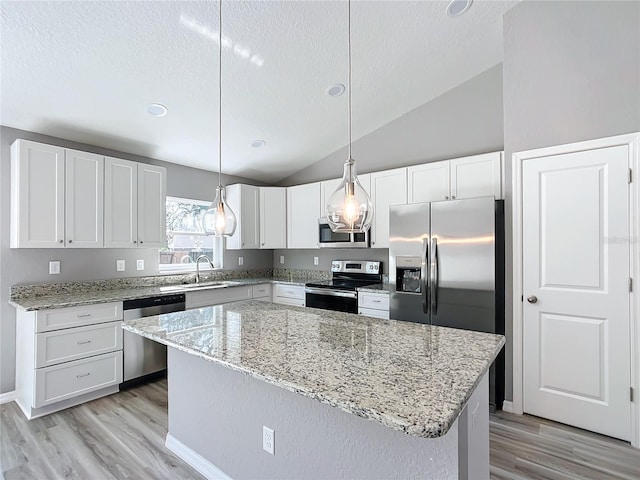 kitchen featuring appliances with stainless steel finishes, hanging light fixtures, a kitchen island, and white cabinets