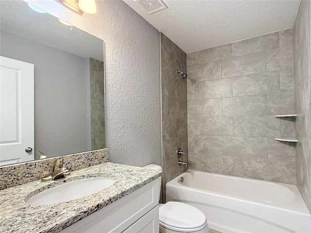 full bathroom with vanity, toilet, tiled shower / bath combo, and a textured ceiling