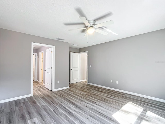 unfurnished bedroom with ceiling fan, wood-type flooring, and a textured ceiling