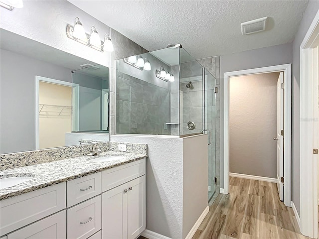 bathroom with walk in shower, vanity, a textured ceiling, and hardwood / wood-style flooring