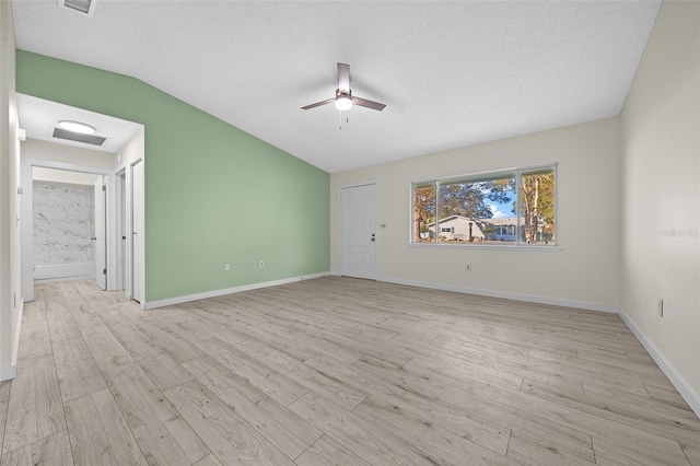 empty room with lofted ceiling, a textured ceiling, ceiling fan, and light hardwood / wood-style floors