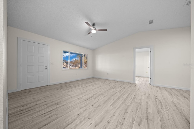 spare room featuring ceiling fan, lofted ceiling, a textured ceiling, and light wood-type flooring