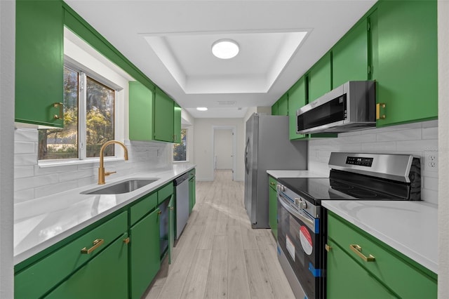 kitchen featuring green cabinets, stainless steel appliances, a raised ceiling, and sink